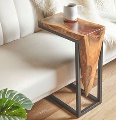 a wooden table sitting on top of a white couch next to a potted plant