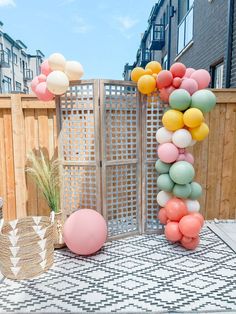 an outdoor party with balloons and decorations on the ground, in front of a wooden fence