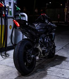 a black motorcycle parked next to a gas pump