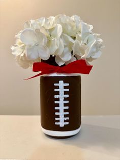 a football vase with white flowers in it