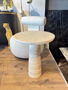 a white chair sitting on top of a hard wood floor next to a table with a dog figurine