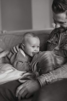 a man is holding a baby on his lap while he looks down at the child's face