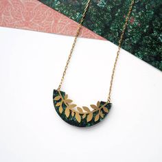 A beautiful delicate gold leaf pendant necklace Featuring a green printed semi circle with a matte gold branch leaf design over played on the surface This piece would add a very modern and quirky addition to anyone's jewellery collection. It is a very versatile piece suitable for everyday wear or a special occasion, it would look simply stunning with any outfit. It is a very fashionable piece and as one of my best sellers would make a great gift for someone you love or little treat for yourself, Gold Leaf Pendant, Gold Branches, Gold Leaf Necklace, Branch Necklace, Modern Necklace, Feuille D'or, Modern Necklaces, Bridesmaid Necklace, Leaf Necklace