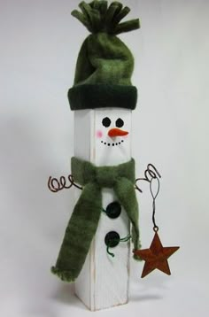 a snowman made out of wood with a green hat and scarf