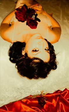 a woman laying on the floor with roses in her hair