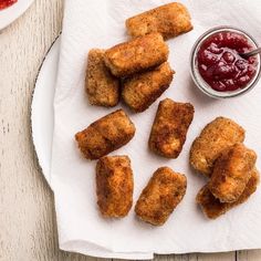 some fried food is on a plate with ketchup and sauces next to it