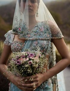 a woman wearing a veil holding a bouquet of flowers