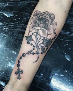 a rose and rosary tattoo on the arm