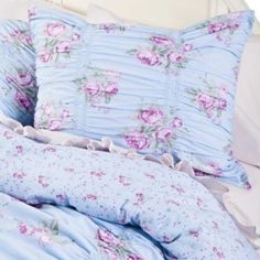 a bed with blue and pink flowers on the comforter, pillows and pillowcases