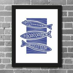 a blue and white fish print hanging on a brick wall next to a black frame