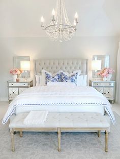 a white bed sitting in a bedroom under a chandelier