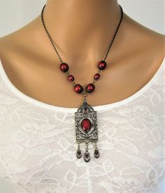 Red Victorian Style Necklace, handmade by Ralston Originals. This red pearl necklace is made with a large antique gold pendant, with red cabochon center, and 3 small charm dangles in antique gold with red crystals. The pendant is 3.5 inches long including the dangles, and 1 inch wide. The pendant is on antique gold brass chain, with dark red glass pearl beads, and antique gold bead caps. This Victorian red necklace is 18 inches long. This necklace is ready to send today, and it includes free shi Vintage Red Jewelry With Dangling Beads, Antique Red Beaded Necklaces For Gift, Antique Red Beaded Necklace For Gift, Antique Red Handmade Necklaces, Antique Red Handmade Necklace, Vintage Red Pendant Beaded Necklace, Vintage Red Necklace With Dangling Beads, Vintage Red Beaded Pendant Necklace, Red Vintage Necklace With Dangling Beads