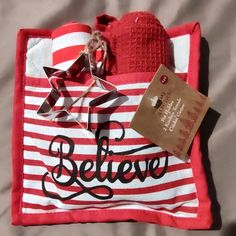 a red and white striped bag sitting on top of a bed next to a tag