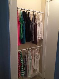 an open closet with clothes hanging on hooks