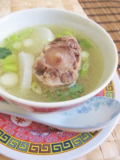 a bowl of soup with meat, celery and broth on a plate