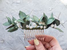 a hand holding a comb with flowers and leaves on it