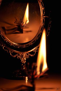 a lit candle in front of a mirror