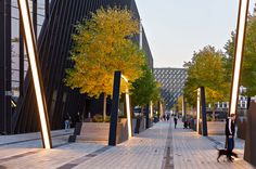 people are walking down the sidewalk in front of tall buildings with trees on both sides