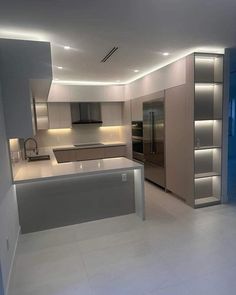 an empty kitchen with stainless steel appliances and lighting on the ceiling is lit by recessed lights