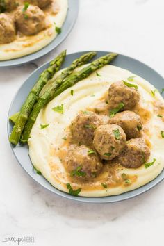 two plates with meatballs and mashed potatoes on them, asparagus in the foreground