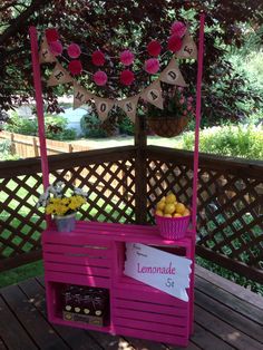 a pink lemonade stand sitting on top of a wooden deck