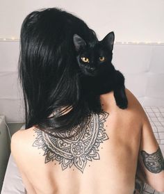 a black cat sitting on top of a woman's back