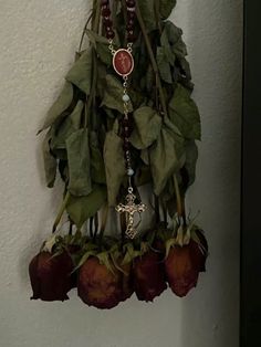 a bunch of flowers hanging from the side of a wall next to a cross and rosary