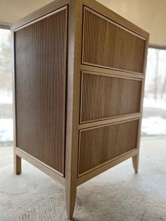 a wooden cabinet sitting on top of a cement floor in front of a window and snow covered ground