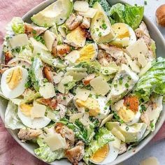 a salad with hard boiled eggs and lettuce in a white bowl on a pink towel