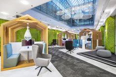 an office with green walls, chairs and tables in the center is decorated with artificial greenery