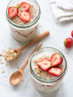 two jars filled with oatmeal and strawberries on top of a table