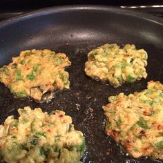 four crab cakes cooking in a frying pan on the stove top with broccoli florets