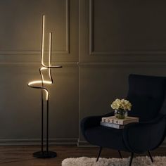 a black chair sitting next to a lamp on top of a wooden floor