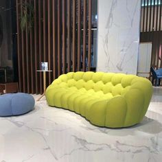 a yellow couch sitting on top of a white floor next to a blue chair and table