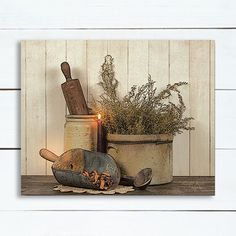 a candle is lit next to an old fashioned pot and pan with herbs in it