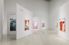 an art gallery with white walls and paintings on the wall, all in different colors