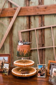 three tiered cake sitting on top of a wooden table next to pictures and framed photos