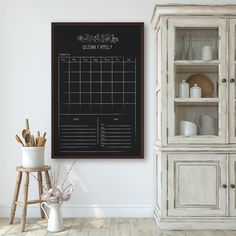 a chalkboard in the corner of a room next to a china cabinet with dishes and utensils