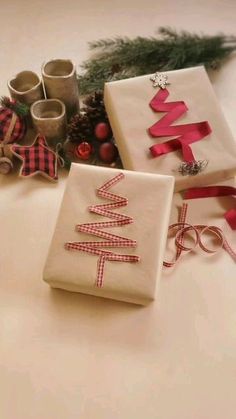 three wrapped presents sitting on top of a table next to some christmas decorations and ribbons