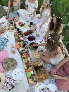 a group of women sitting around a table filled with food