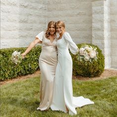 two women standing next to each other in the grass