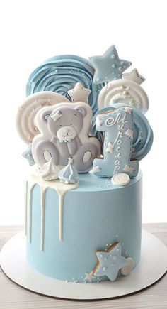 a blue and white cake with teddy bears on it's top, surrounded by other decorations