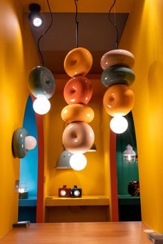 an assortment of doughnuts hanging from the ceiling in a room with yellow walls