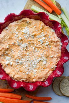 carrots, celery, and crackers in a bowl on a cutting board