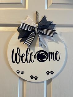 a welcome sign hanging on the front door with paw prints and a ribbon attached to it