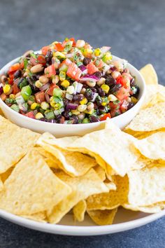 a white bowl filled with black bean salsa surrounded by tortilla chips