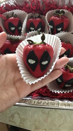 someone is holding some strawberries in their hand with spiderman face decorations on them