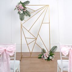 the wedding arch is decorated with pink flowers and greenery, along with white chairs