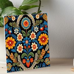 a colorful floral design on a black background art boarder next to a potted plant