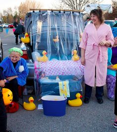 several people standing around in front of a car with rubber ducks on the floor and one person wearing a pink bathrobe